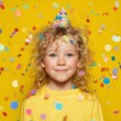 © Ouzhan - A joyful child wearing a party hat, surrounded by confetti, ready to celebrate