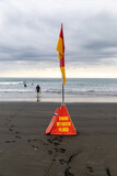 Swimmers and surfers stay safe by swimming between the flags on a beach in New Zealand, marked by Surf Life Saving. Karekare, Auckland, New Zealand