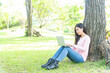 © tonjung - Lifestyle person Woman listening music and reading a book and play laptop on the grass field of the nature park in the morning . Concept lifestyle