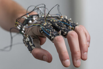 Poster - A close up of a hand wearing a wired device with circuit boards attached to each of the fingers and hand