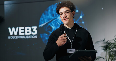 Poster - Man, tablet and mic for presentation with web3, decentralization and blockchain by screen for future. Person, speaker and touchscreen with app, innovation and discussion on stage at tech convention