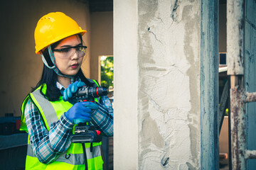 Wall Mural - Female worker is using a drill to drill a pole.
