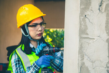 Wall Mural - Female worker is using a drill to drill a pole.