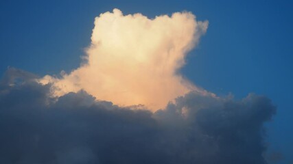 Poster - A captivating display of towering cloud formations glows as sunlight grazes their edges, creating a serene and beautiful atmosphere in the evening sky