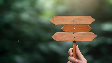 Poster - Businessman hand holding wooden directional sign with changing arrows. Isolated on a blurred background with bokeh effect. Representing the difficulty of making a decision and choosing the right path