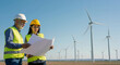 © ArtMajestic - Senior man and woman engineer reviewing blueprint at wind farm. Industry professionals at turbine park planning renewable energy project, with copy space