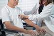 © NINENII - Doctor with stethoscope examining elderly patient sitting in a wheelchair with examination, recommending treatment, healthcare and medical concept.