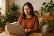 © Alice_Fame - Happy woman working remotely on laptop at home, cozy apartment with houseplants, home office concept, freelance lifestyle, modern work from home scene