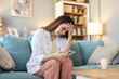© Jelena Stanojkovic - House, stress and woman with cellphone, headache and mistake with communication. Person, apartment and girl on couch, illness and smartphone with migraine, online reading and sick with error message.