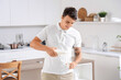 © Pixel-Shot - Young man pouring milk from bottle into glass in kitchen