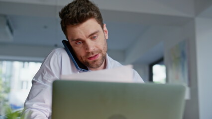 Poster - Multitasking businessman talking cellphone reading documents in office closeup.