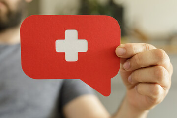 Poster - Hand holding a red speech bubble with a white plus sign.  Medical, healthcare, help concept.