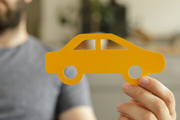Poster - A person holds a yellow paper cutout of a car.  Concept for car insurance, buying a car, or transportation.