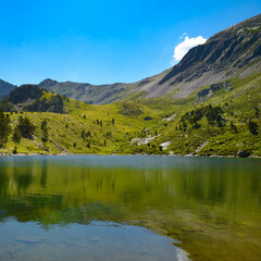 Wall Mural - Picturesque lake high in the mountains against the backdrop of bright sky.