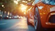 © Moments In Frame - Orange Sports Car at Sunset: A close-up of a sleek, orange sports car parked on a city street at sunset. The warm glow of the setting sun illuminates the car's metallic paint.
