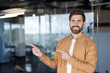 © Liubomir - A smiling man in a smart casual outfit points towards an area with both hands, likely presenting something.