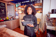 © oscargutzo - Confident black female barista using digital tablet in coffee shop