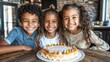 © Weather - Three smiling children sit together at a wooden table, happily posing in front of a delicious-looking cake.  A warm, inviting cafe setting is visible in the background