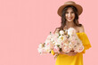 © Pixel-Shot - Young woman in hat with peony flowers on pink background