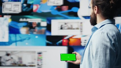 Poster - Young adult checks green screen on phone as a user interface, checking online presence on social platforms. Male Influencer working on creativity and online engagement in a digital world. Camera B.