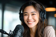 © sornram - A joyful woman wearing headphones, radiating positivity while engaging in a podcast recording. Bright and inviting atmosphere.
