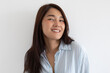 © Suthida - Asian woman smiling gently in light striped shirt isolated over white background wall.