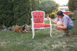 © erika8213 - Woman painting a wooden furniture while sitting with her dog in the garden. DIY concept.