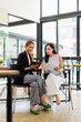 © David - Two asian business women sit at desk discuss project details, diverse female colleagues planning financial graph report in the office, share opinion