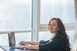 © dmitriisimakov - woman working on laptop online and smiling in office