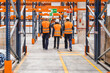 © Koldo_Studio - Warehouse workers in safety vests and hard hats navigating through a spacious logistics center, ensuring efficient operation and organization