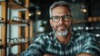 © Pinklife - A middle-aged man with a beard stands smiling in an eyeglasses store, showcasing his style and confidence, highlighting the importance of self-image and personal choices.