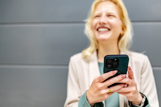 Young woman with albinism smiles while using her smartphone in a modern indoor setting during daytime