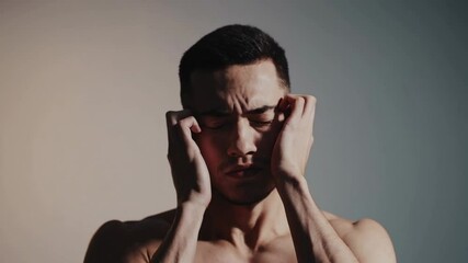 Aufkleber - Shirtless young male experiencing intense head pain, massaging face while displaying clear signs of physical and mental discomfort in isolated studio environment