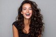 © Lubos Chlubny - Beautiful smiling girl with long wavy hair is laughing on gray background