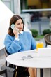© nazariykarkhut - Young woman talking on smartphone and drinking orange juice at outdoor cafe