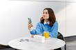 © nazariykarkhut - Businesswoman using smartphone and drinking orange juice at outdoor cafe
