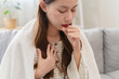 © Pormezz - Unforeseen Discomfort: A Woman Experiences a Sudden Cough, Close-up of a woman coughing and feel chest pain.