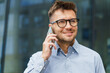 © muse studio - Businessman Networking Outdoors During Sunny Day While Engaged in Important Phone Call Near Modern Office Building