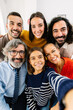 © Xavier Lorenzo - Vertical photo of large group of cheerful family members taking a selfie together, smiling and looking at camera enjoying time at home.