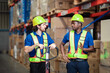 © Wanwajee - Two warehouse workers push a loaded cart while discussing tasks and pointing directions, showing teamwork in logistics operations.