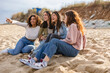 © PintoArt - Four young women pointing and laughing together on beach