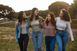 © PintoArt - Four young women walking together in a park, enjoying friendship and nature
