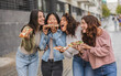 © PintoArt - Cheerful young women eating pizza slices in the city