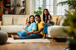 © StockImageFactory - Smiling Indian family sitting on floor near sofa, bonding together in stylish cozy living room