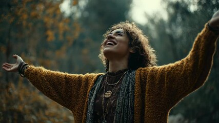 Wall Mural - young woman with curly hair wearing brown sweater and scarf standing among forest trees, head tilted