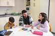 © Antonio Recena - Father in the kitchen of his home helps his son and daughter with their homework on an autumn day