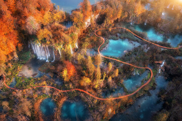 Wall Mural - aerial view of waterfall in red autumn forest at sunrise. morning in plitvice lakes park, croatia. c