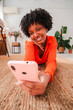 © Jose Calsina - Happy female enjoying her smartphone, lying comfortably on a soft rug and interacting with fascinating applications, immersed in her digital world while conveying a sense of relaxation and joy