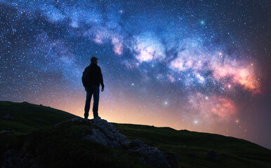 Wall Mural - Glowing Milky Way and man on mountain trail at starry night. Silhouette of a guy on the hill, sky with bright stars. Galaxy. Space landscape with milky way. Nightscape. Travel background. Concept