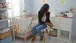 © Krakenimages.com - Woman sitting bedroom tying baby shoes near cradle surrounded by cozy decor and soft lighting in a warm indoor setting enhancing familial and nurturing atmosphere.